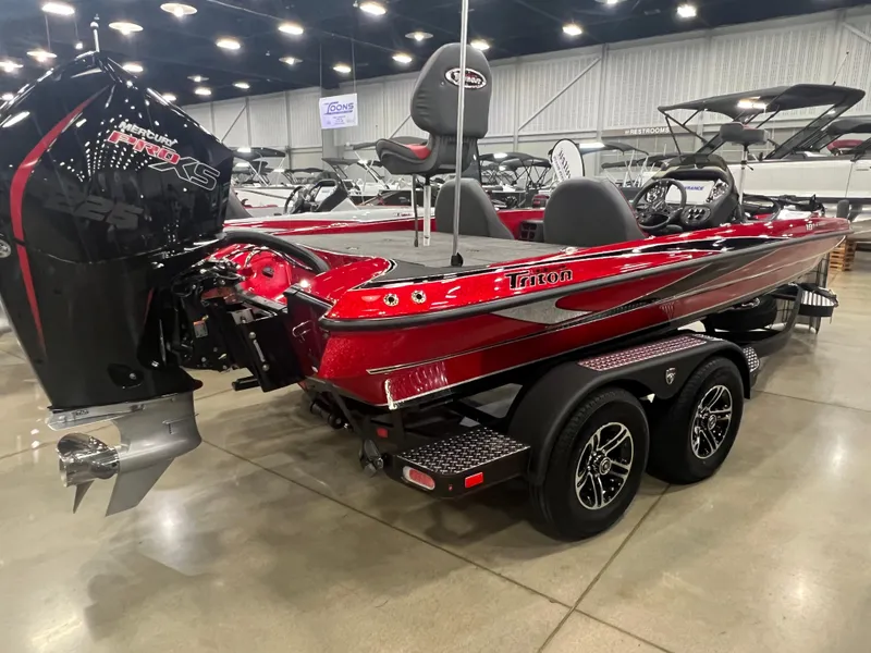 Slide: The Image of 2024 Triton 19 TrX Patriot bass boat in showroom, red and black, dual-axle trailer. - 4