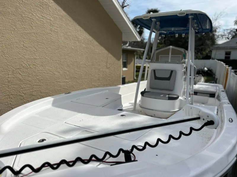 Slide: The Image of 2020 Aquasport 244 Bay boat with T-top and seating, docked near a house. - 20