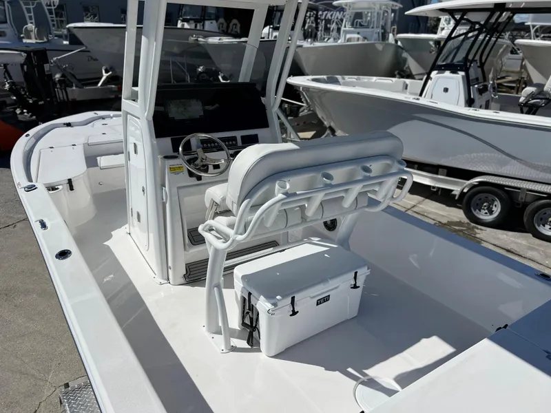 Slide: The Image of 2024 Sea Fox 251 Bay Fox boat with white cushioned seating and outboard motor. - 29