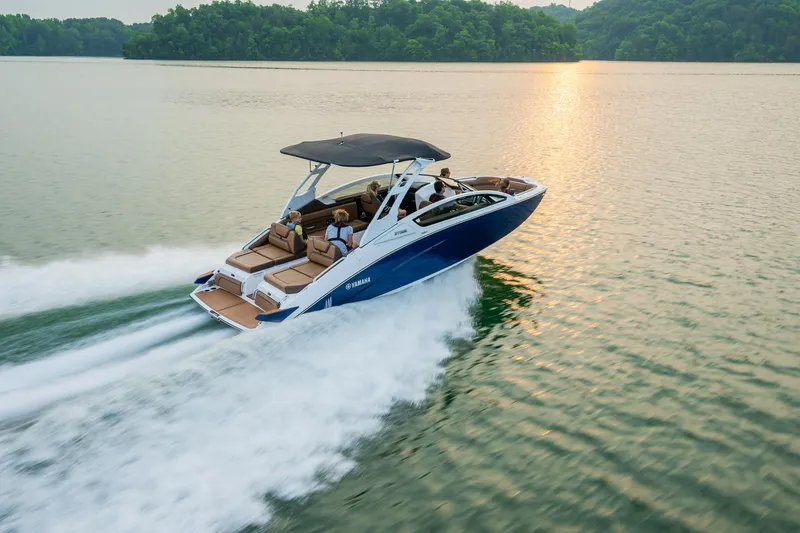 Slide: The Image of 2024 Yamaha Boats 275SE cruising on a serene lake at sunset. - 11