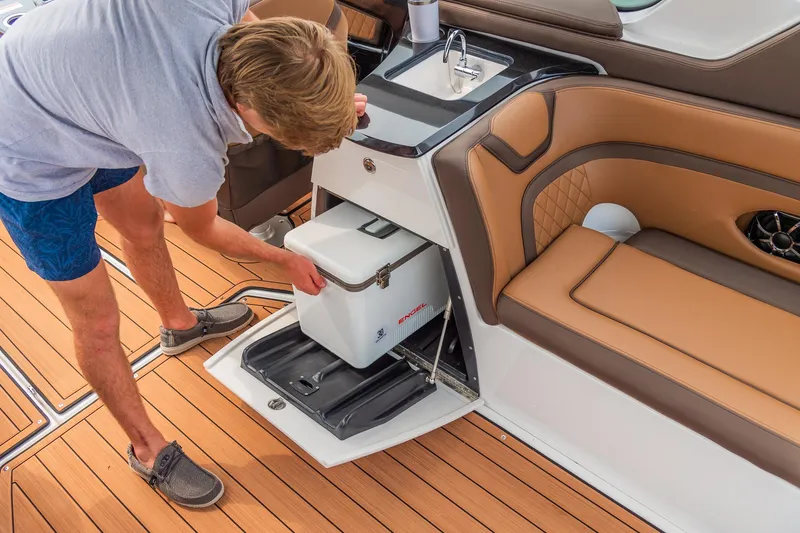 Slide: The Image of Man accessing cooler on 2024 Yamaha Boats 275SE, luxury boat interior. - 6