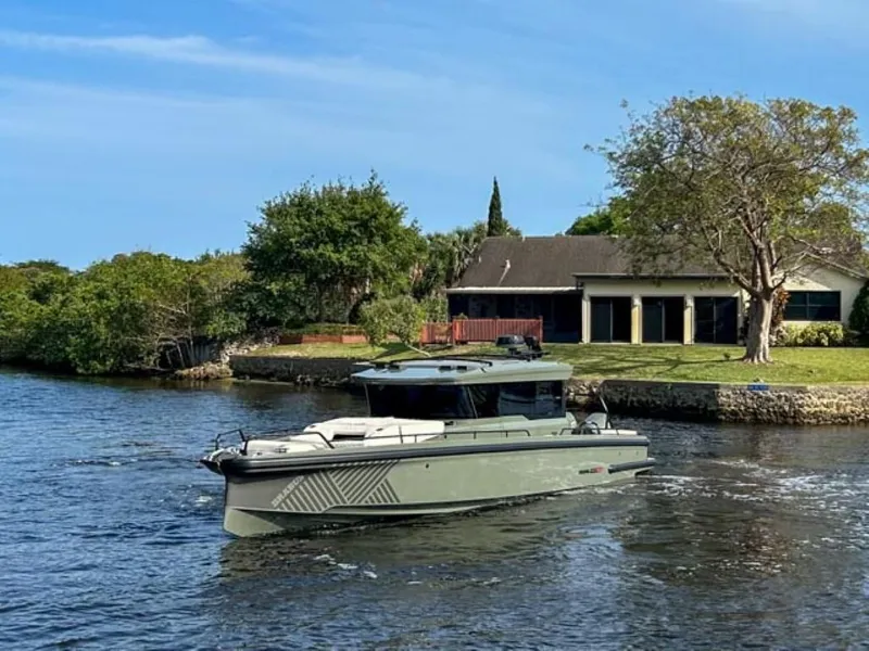 Slide: The Image of 2024 BRABUS Shadow 900XC boat cruising on a serene river near a house. - 2