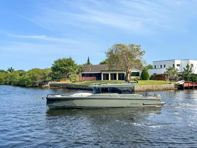 Slide: The Image of 2024 BRABUS Shadow 900XC boat cruising on a scenic river near luxury homes. - 3