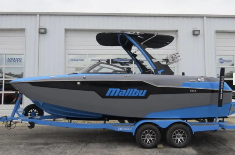 Slide: The Image of 2023 Malibu M220 boat on trailer outside dealership. - 1