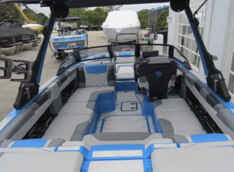 Slide: The Image of 2023 Malibu M220 boat interior with blue and gray seating, docked at marina. - 10