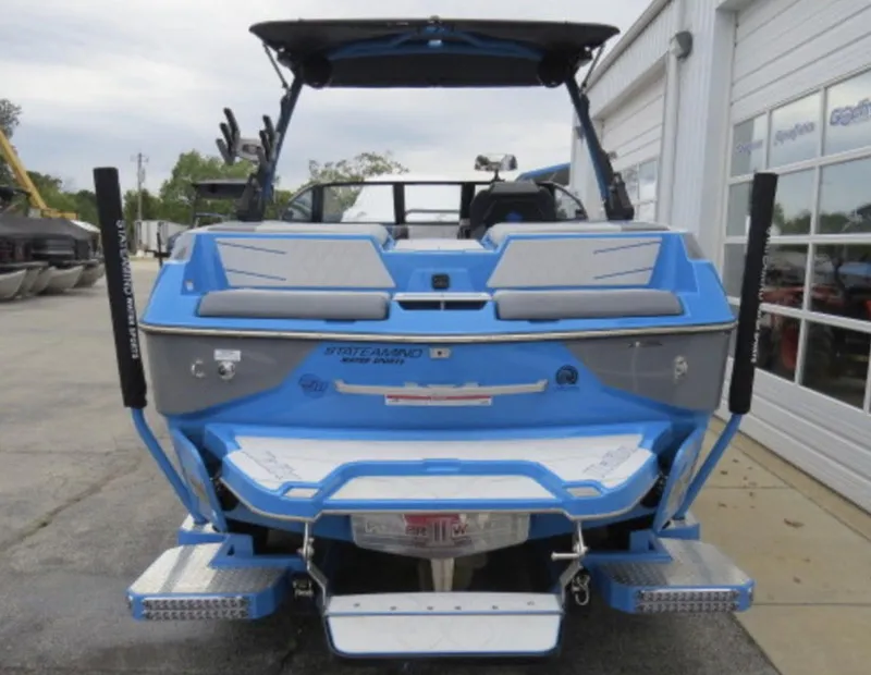 Slide: The Image of 2023 Malibu M220 boat rear view with blue and gray detailing. - 4