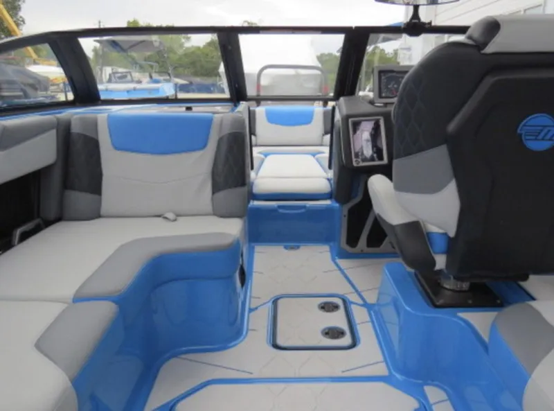 Slide: The Image of 2023 Malibu M220 boat interior with blue and gray seating and modern dashboard. - 7