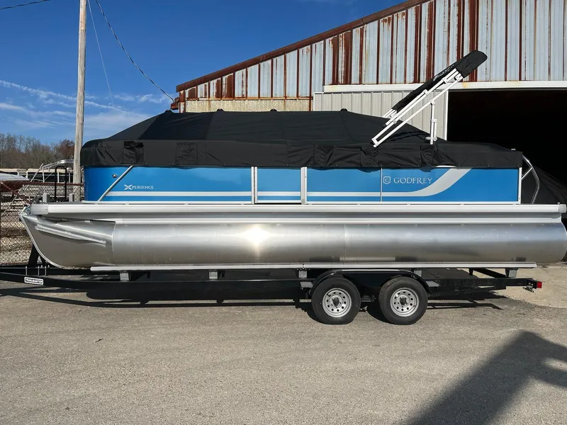 Slide: The Image of 2024 Sweetwater 2286SBCX pontoon boat on a trailer, covered and parked outdoors. - 0