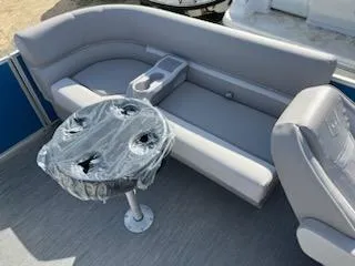 Slide: The Image of 2024 Sweetwater 2286SBCX boat interior with gray seating and table. - 12