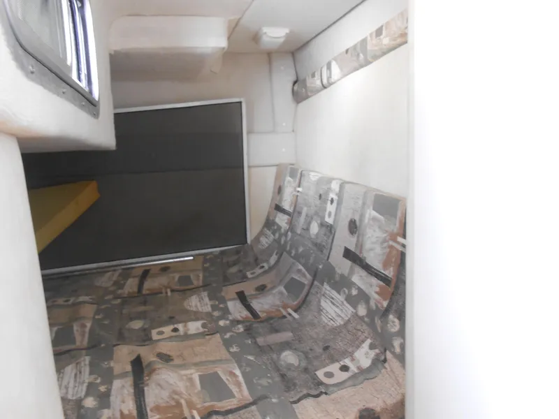 Slide: The Image of Interior cabin of 2003 Glastron GS249 boat with patterned seating and white walls. - 25