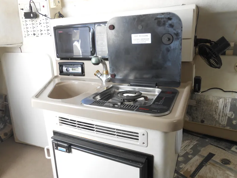 Slide: The Image of 2003 Glastron GS249 boat kitchenette with stove, sink, and mini fridge. - 27