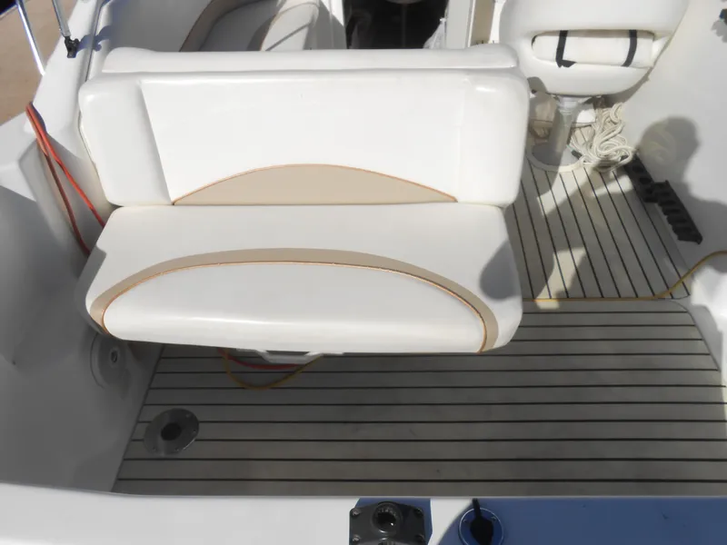 Slide: The Image of 2003 Glastron GS249 boat interior with white seating and striped flooring. - 5