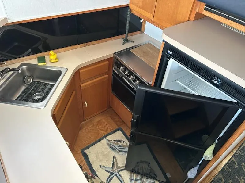 Slide: The Image of Compact kitchen in a 1990 Silverton AFT CABIN boat with sink, stove, and refrigerator. - 15