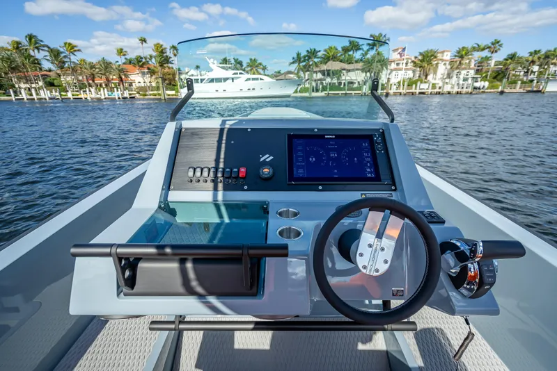 Slide: The Image of 2024 Goldfish 28 Tender boat dashboard with steering wheel and navigation system on a sunny day. - 18