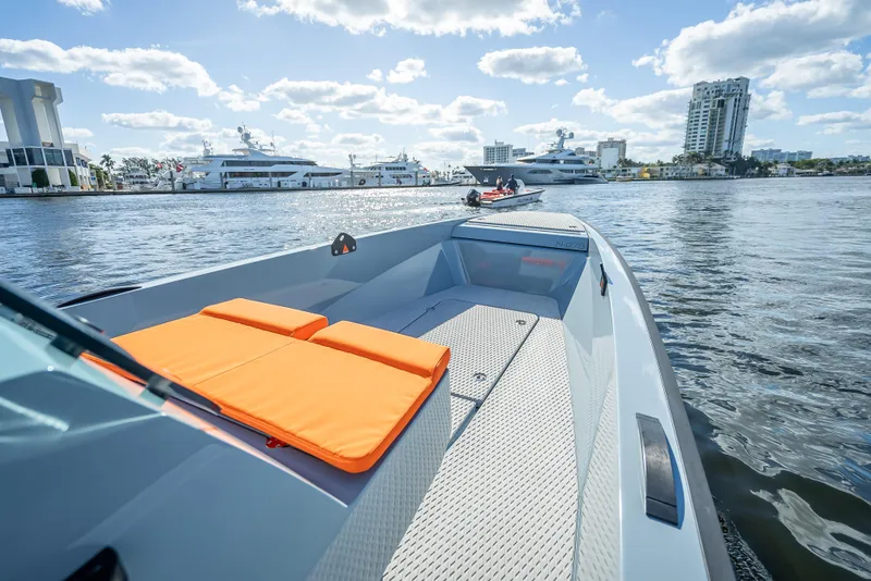Slide: The Image of 2024 Goldfish 28 Tender boat on water with orange cushions, cityscape in background. - 23