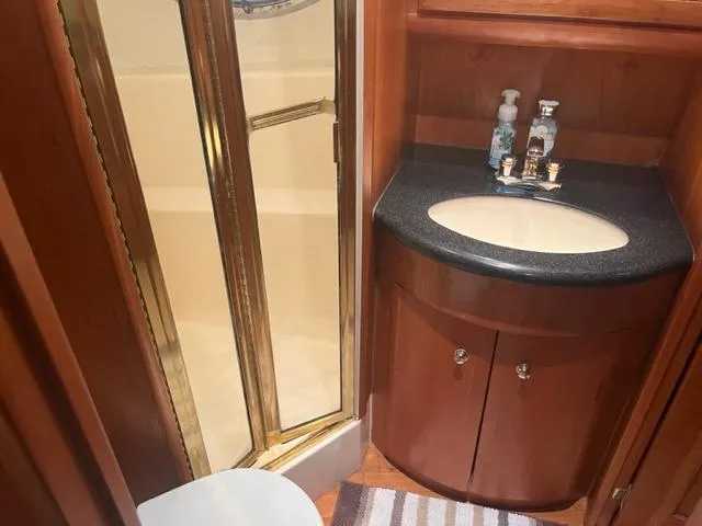 Slide: The Image of 2002 Silverton 39 Motor Yacht bathroom with shower, sink, and wooden cabinetry. - 10