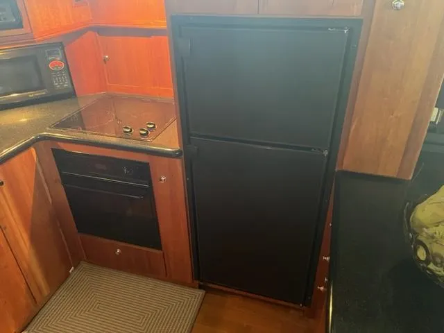 Slide: The Image of 2002 Silverton 39 Motor Yacht kitchen with stove, oven, microwave, and refrigerator. - 12
