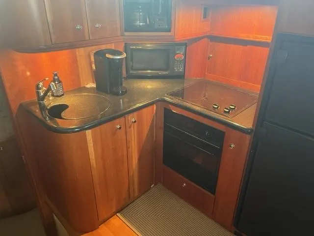 Slide: The Image of 2002 Silverton 39 Motor Yacht kitchen with microwave, stove, sink, and refrigerator. - 13