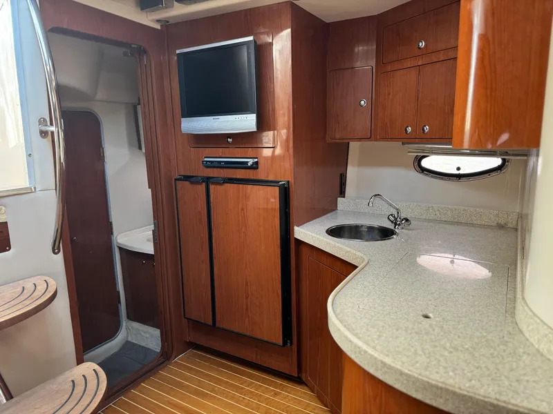 Slide: The Image of 2007 Regal 4060 COMMODORE yacht interior with kitchenette, TV, and wooden cabinetry. - 22