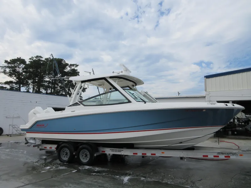 The Image of 2021 Boston Whaler 280 Vantage boat on a trailer, blue hull, outdoor setting. - 0