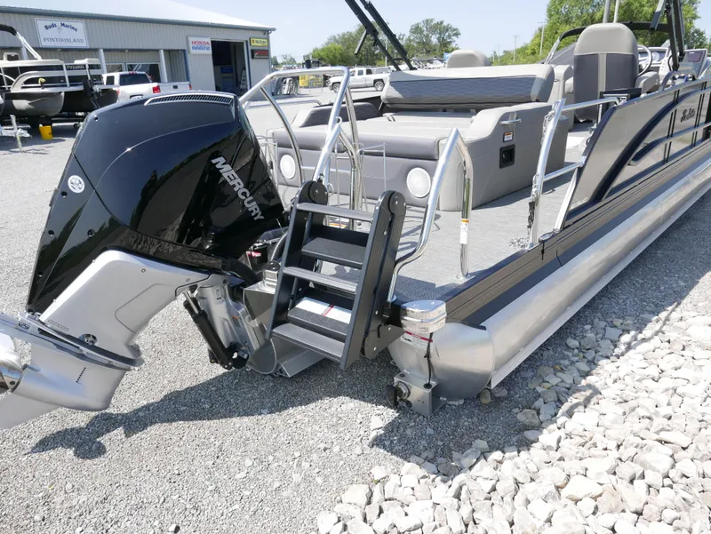 Slide: The Image of 2024 Barletta Corsa 23UC pontoon boat with Mercury engine, docked on gravel. - 4