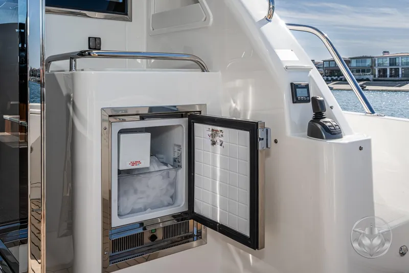 Slide: The Image of Open ice maker on 2026 Riviera 395 SUV yacht, docked by waterfront homes. - 21