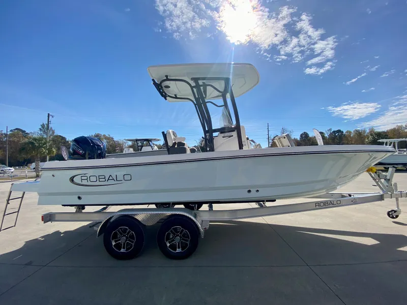 Slide: The Image of 2024 Robalo 226 Cayman boat on a trailer under a sunny sky. - 4