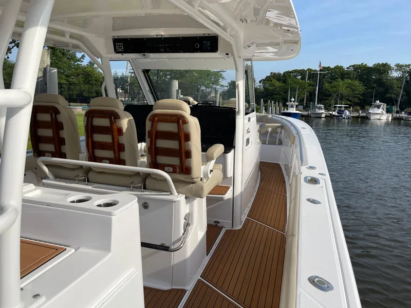 Slide: The Image of 2019 Everglades 435 CC boat interior with seating, wood flooring, and water view. - 12