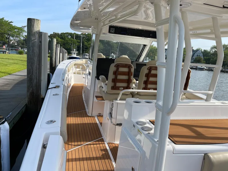Slide: The Image of 2019 Everglades 435 CC boat docked, featuring spacious deck and luxurious seating. - 21