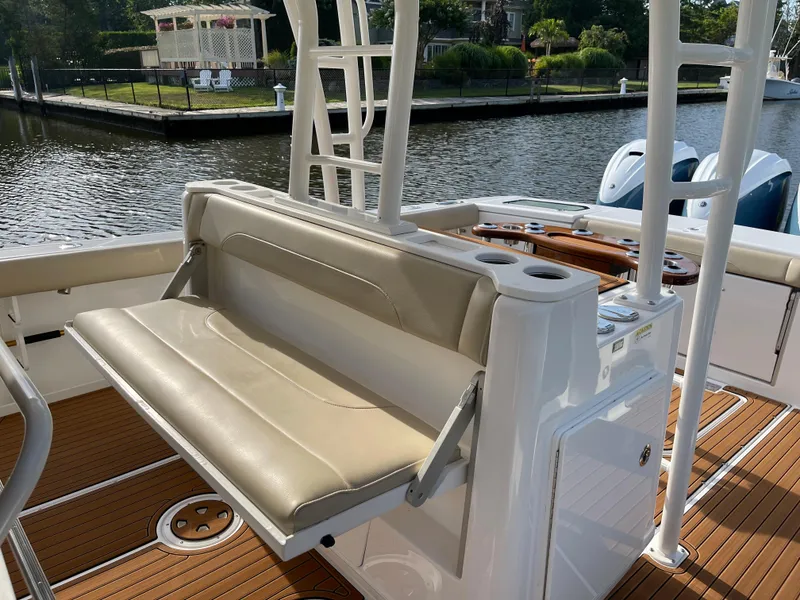 Slide: The Image of 2019 Everglades 435 CC boat interior with beige seating and wooden deck by the water. - 23