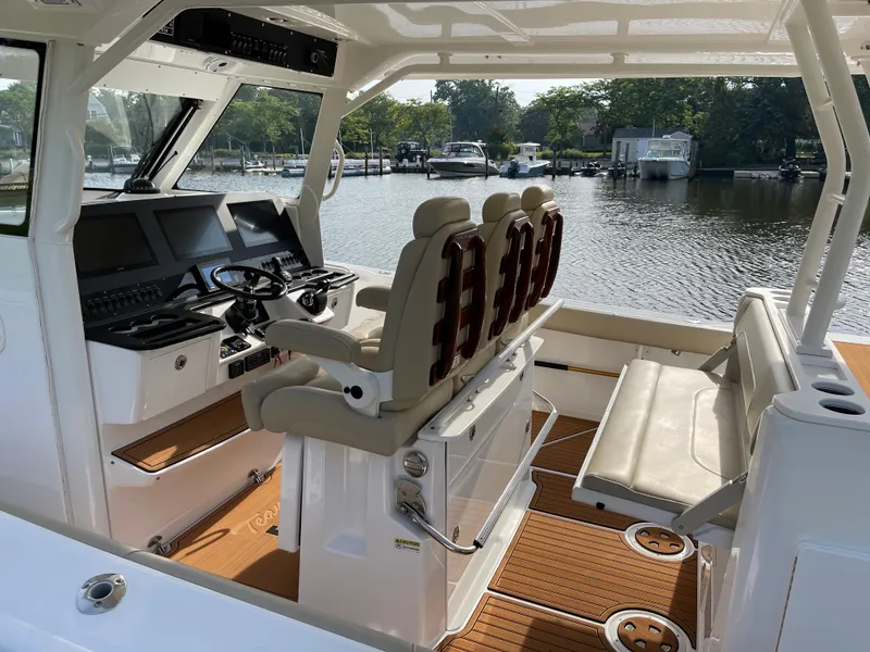 Slide: The Image of 2019 Everglades 435 CC boat interior with helm seats and waterfront view. - 24