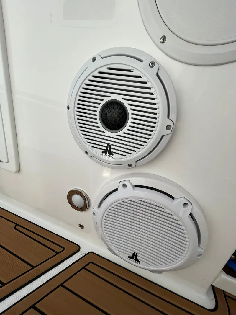 Slide: The Image of Speakers on 2019 Everglades 435 CC boat, featuring sleek white design and wood-patterned flooring. - 36