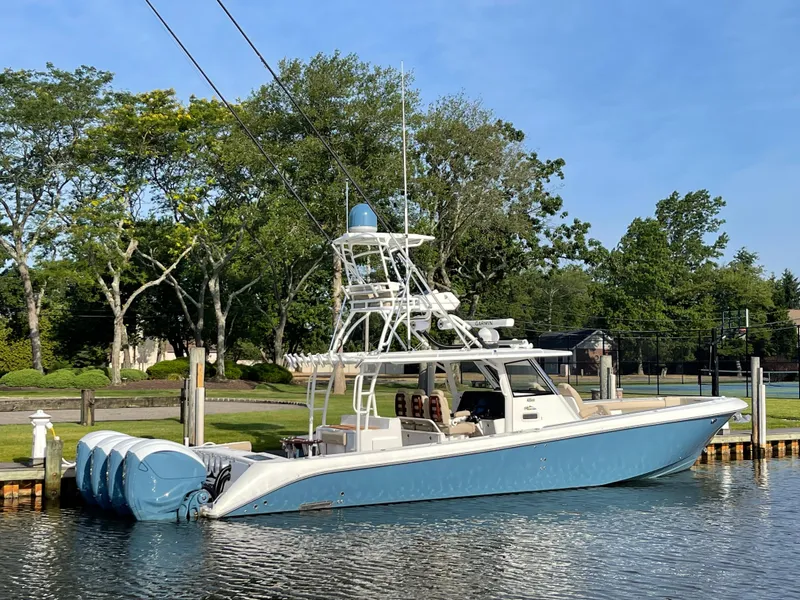 Slide: The Image of 2019 Everglades 435 CC boat docked on a calm waterway, surrounded by lush greenery. - 4
