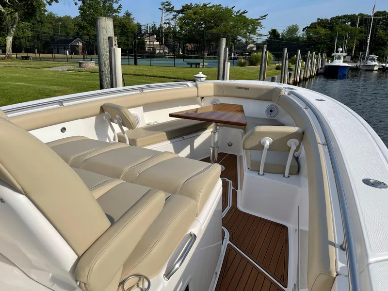 Slide: The Image of 2019 Everglades 435 CC boat with beige seating and wooden deck, docked by a marina. - 48