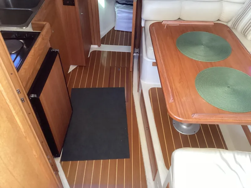Slide: The Image of 2002 Mainship 34 PILOT interior with wood flooring, dining table, and kitchenette. - 11