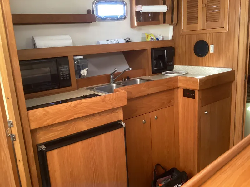 Slide: The Image of 2002 Mainship 34 PILOT boat kitchen with wood cabinetry, sink, and appliances. - 17