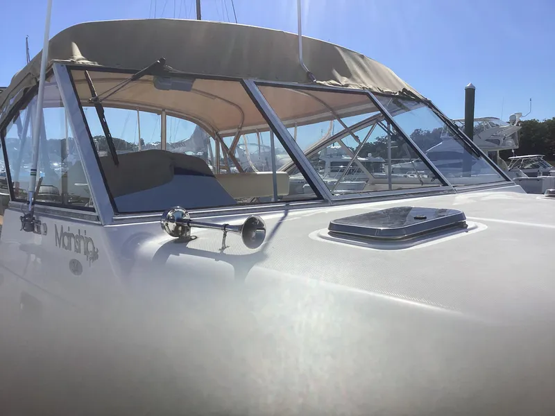 Slide: The Image of 2002 Mainship 34 PILOT boat with beige canopy in marina setting. - 4
