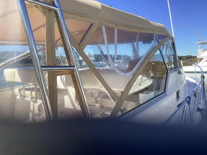 Slide: The Image of 2002 Mainship 34 PILOT boat with beige canopy and clear windows, docked in a marina. - 5