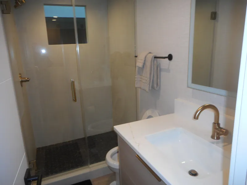 Slide: The Image of Modern bathroom with glass shower, white sink, and gold fixtures. Adonia Radiance Share #12, 2022. - 24