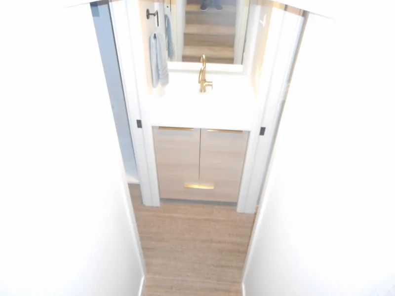 Slide: The Image of Modern bathroom with gold faucet, white vanity, and light wood cabinets in Adonia Radiance Share #12, 2022. - 27