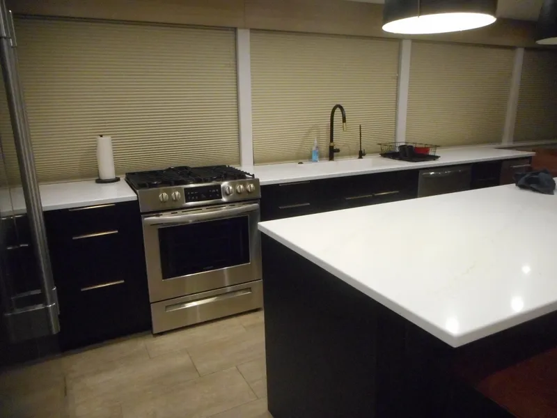 Slide: The Image of Modern kitchen with stainless steel appliances, white countertops, and dark cabinetry, featuring Adonia Radiance Share #12. - 35