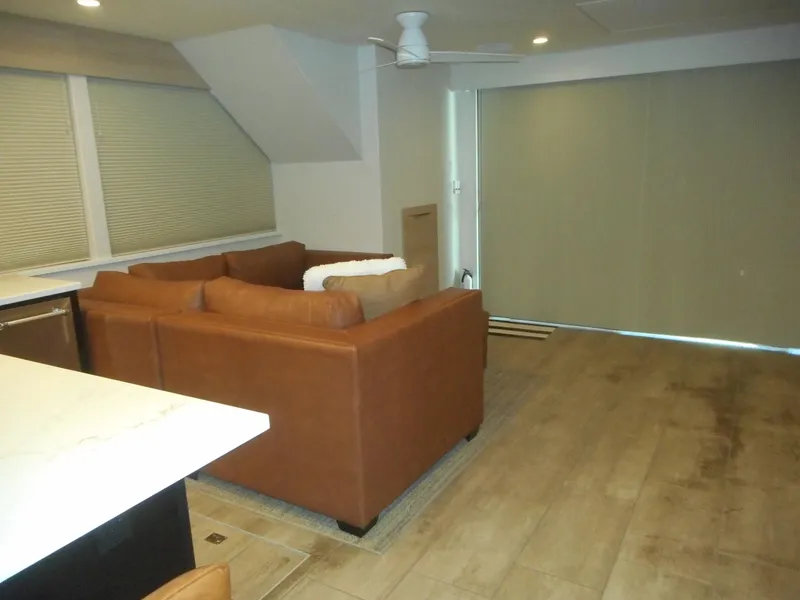 Slide: The Image of Modern living room with brown sectional sofa, wooden flooring, and large window blinds. Adonia Radiance Share #12, 2022. - 40