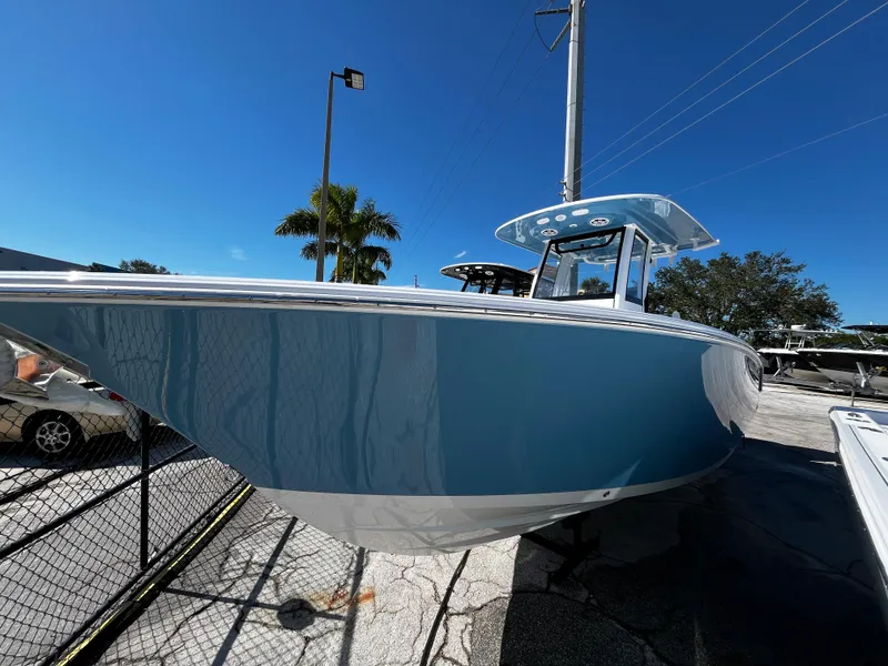Slide: The Image of 2024 Sportsman Open 252 Center Console boat in blue, docked under clear sky. - 1