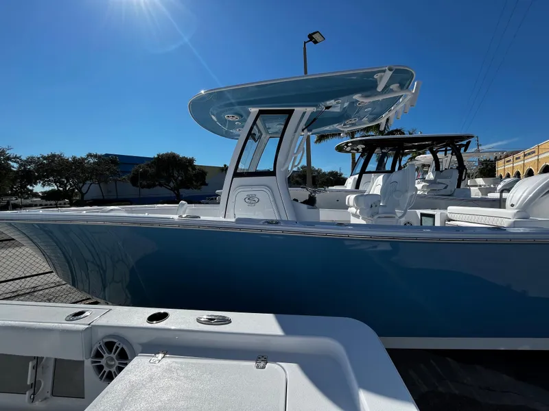 Slide: The Image of 2024 Sportsman Open 252 Center Console boat in a marina under clear blue sky. - 2