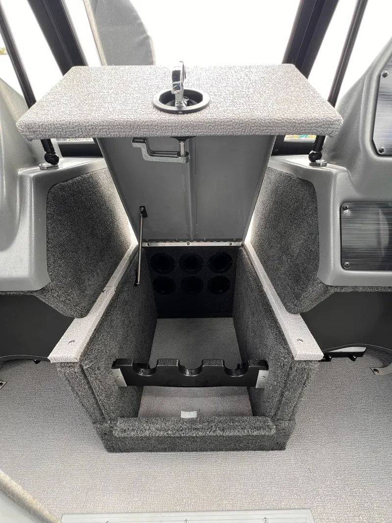 Slide: The Image of 2024 Starcraft Renegade 168 DC boat storage compartment with rod holders and carpeted interior. - 14