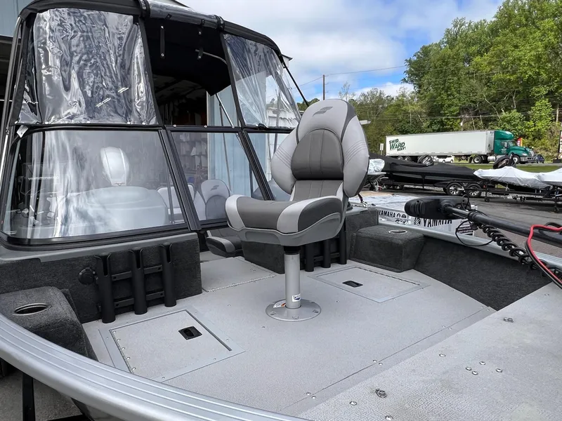 Slide: The Image of 2024 Starcraft Renegade 168 DC boat interior with seating and windshield, parked outdoors. - 32