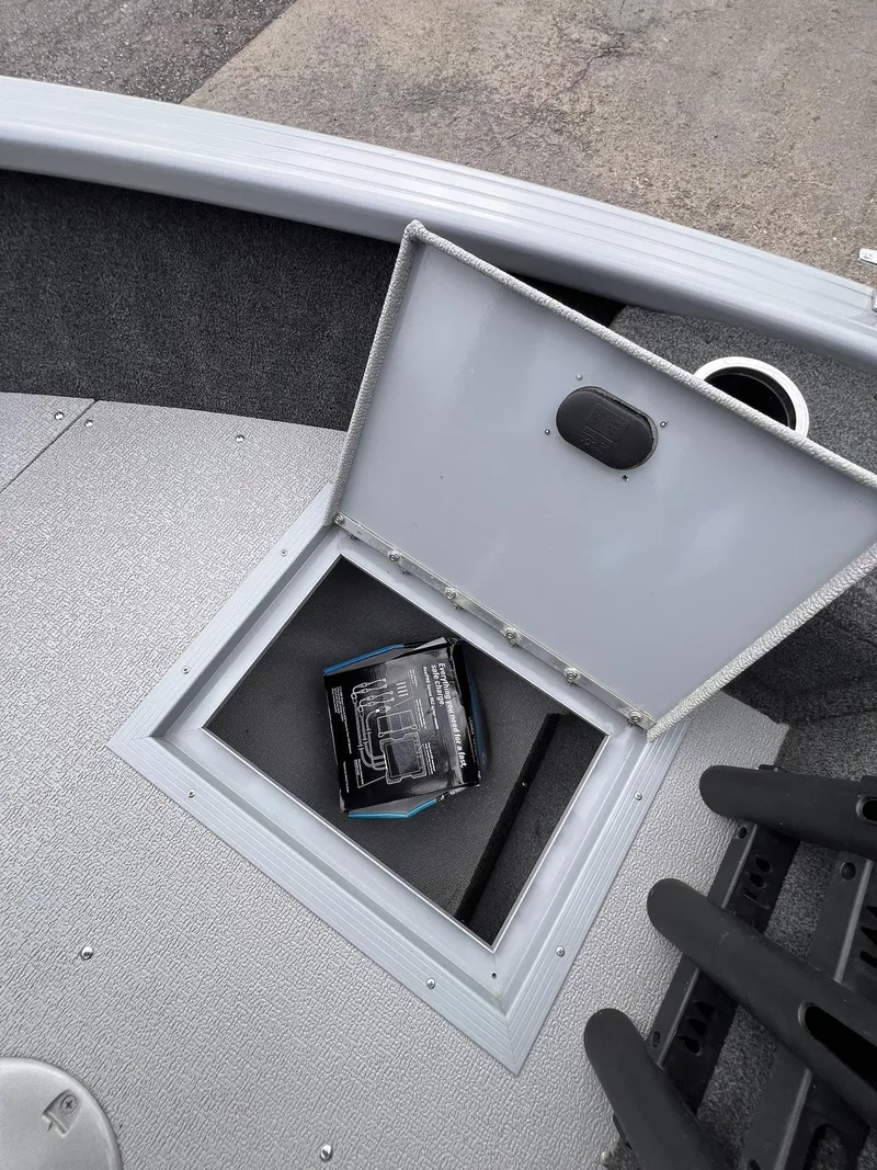 Slide: The Image of 2024 Starcraft Renegade 168 DC boat storage compartment with open lid and item inside. - 38
