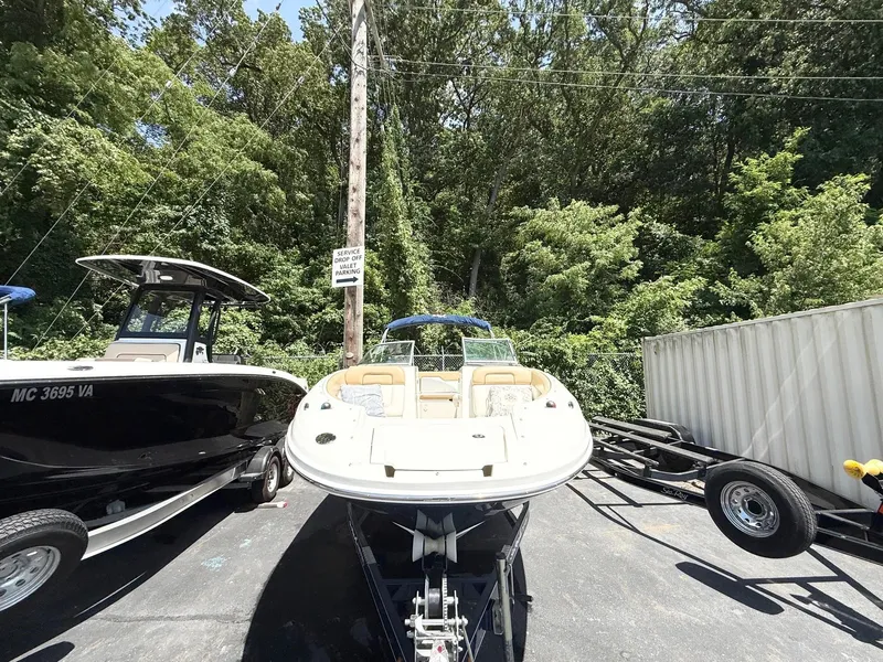Slide: The Image of 2011 Sea Ray 240 Sundeck boat on trailer, surrounded by trees and parked vehicles. - 3