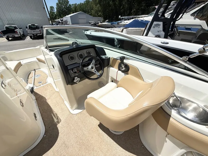 Slide: The Image of 2011 Sea Ray 240 Sundeck boat interior with steering wheel and beige seating. - 7
