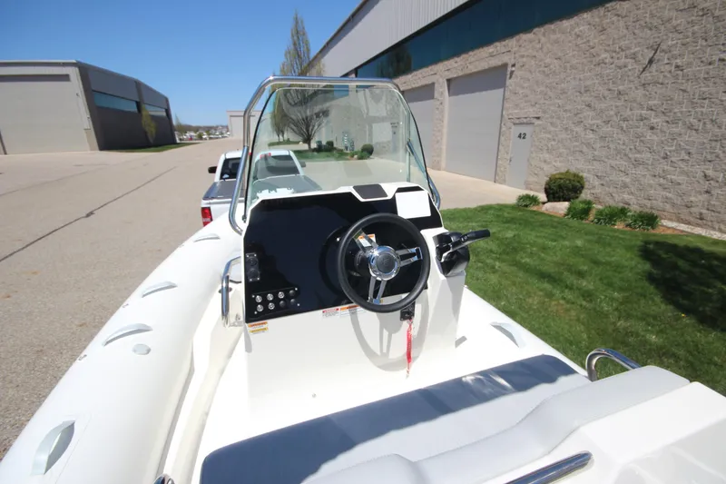 Slide: The Image of 2025 Zodiac Medline 5.8 NEO boat with 115hp engine, parked outdoors near industrial buildings. - 17